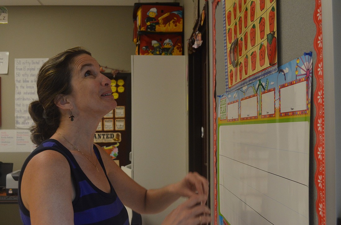 Imagine School at Palmer Ranch first-grade teacher Sarah Walsh sticks months of the year over the colorful calendar in preparation for the first day of school Monday, Aug. 19.
