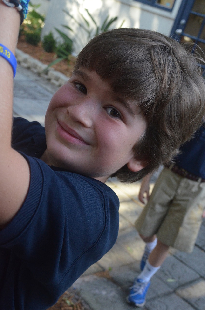 Fourth-grader Tristan J. ties a knot after his classmate raises the flag.