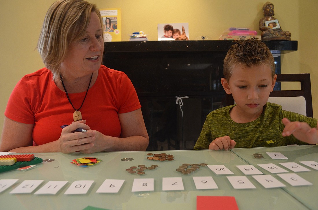 Ian Arov, 5, organizes coins into separate areas depending on their value. He tells kindergarten teacher Shonna Brady the value of each coin.