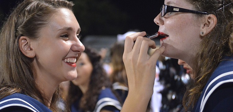 Senior Valorie Gochnauer touches up Lacey Landers' make-up during the game.
