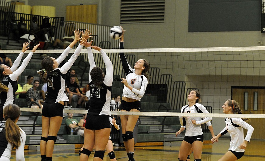 Sarasota junior middle hitter Toni Mogensen looks to get the ball past a pair of Lakewood Ranch defenders.