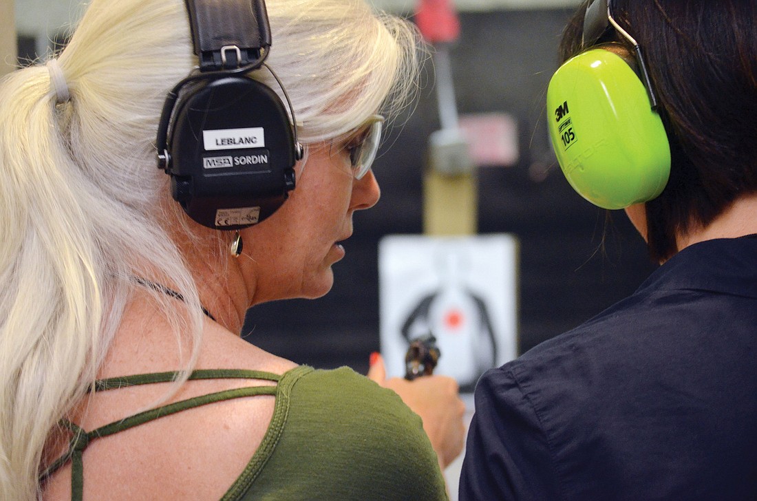 Experienced shooter Jennifer LeBlanc helps beginner Michelle Carpenter with target practice.