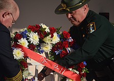 Sarasota County Fire Chief Mike Tobias and Sarasota County Sheriff's Office Col. Steve Burns place a wreath of flowers next to the 9/11 memorial plaque at the Sarasota County Police Department.