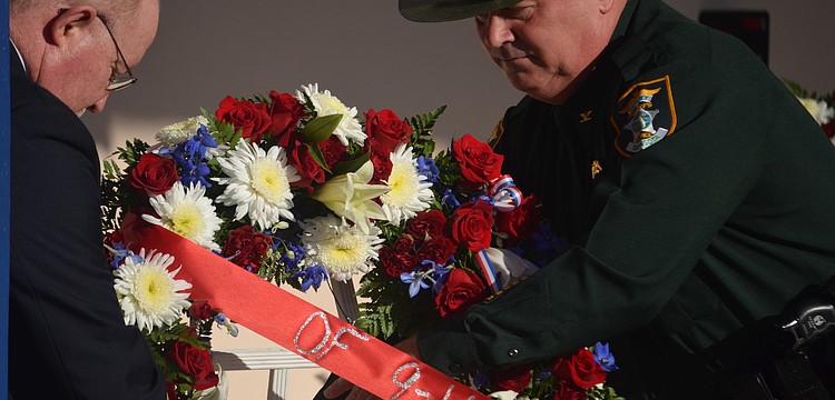 Sarasota County Fire Chief Mike Tobias and Sarasota County Sheriff's Office Col. Steve Burns place a wreath of flowers next to the 9/11 memorial plaque at the Sarasota County Police Department.