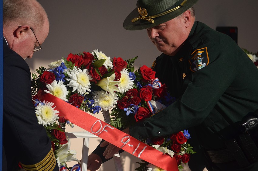 Sarasota County Fire Chief Mike Tobias and Sarasota County Sheriff's Office Col. Steve Burns place a wreath of flowers next to the 9/11 memorial plaque at the Sarasota County Police Department.