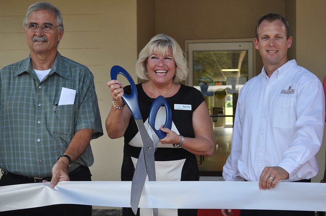 Community Haven Chairman Ted Bogusz, President and CEO Marla Doss and Tom Rees help cut the ribbon.