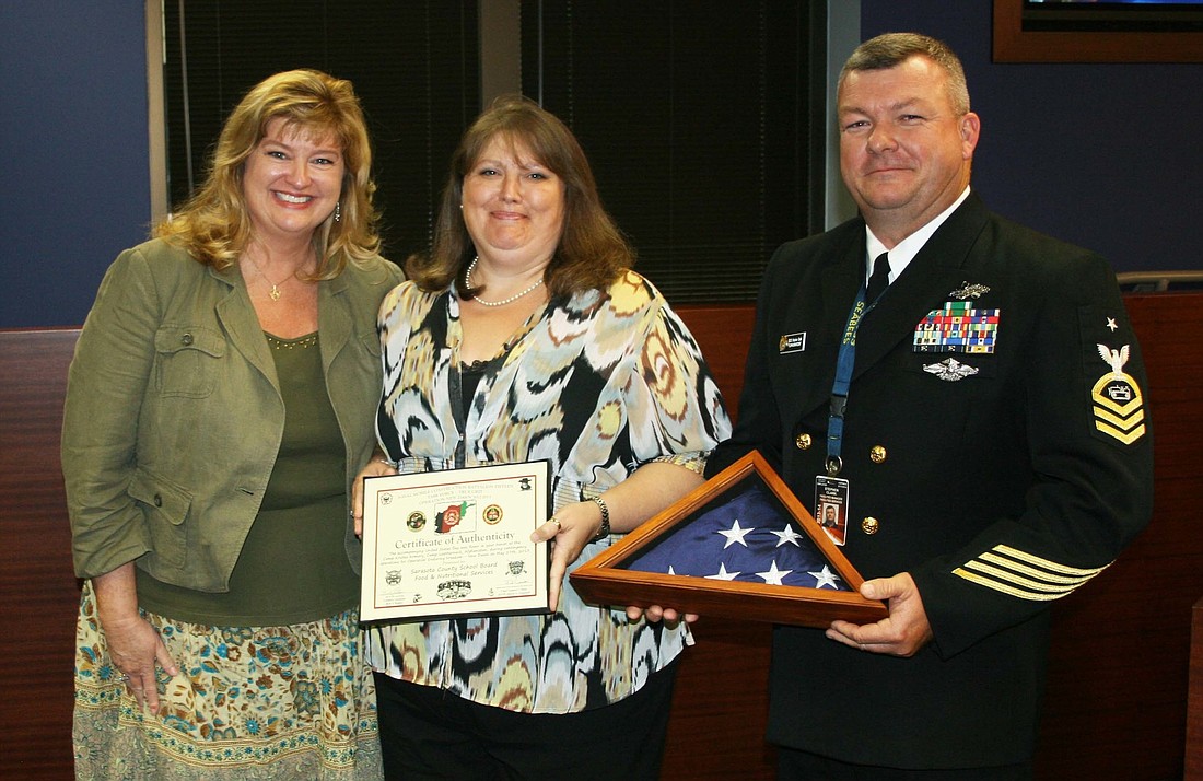 Senior Chief Petty Officer Steve Clark and his wife Valeta Clark, present an American Flag that flew over a base in Afghanistan to Sarasota County Schools Food and Nutrition Services Director Beverly Girard.