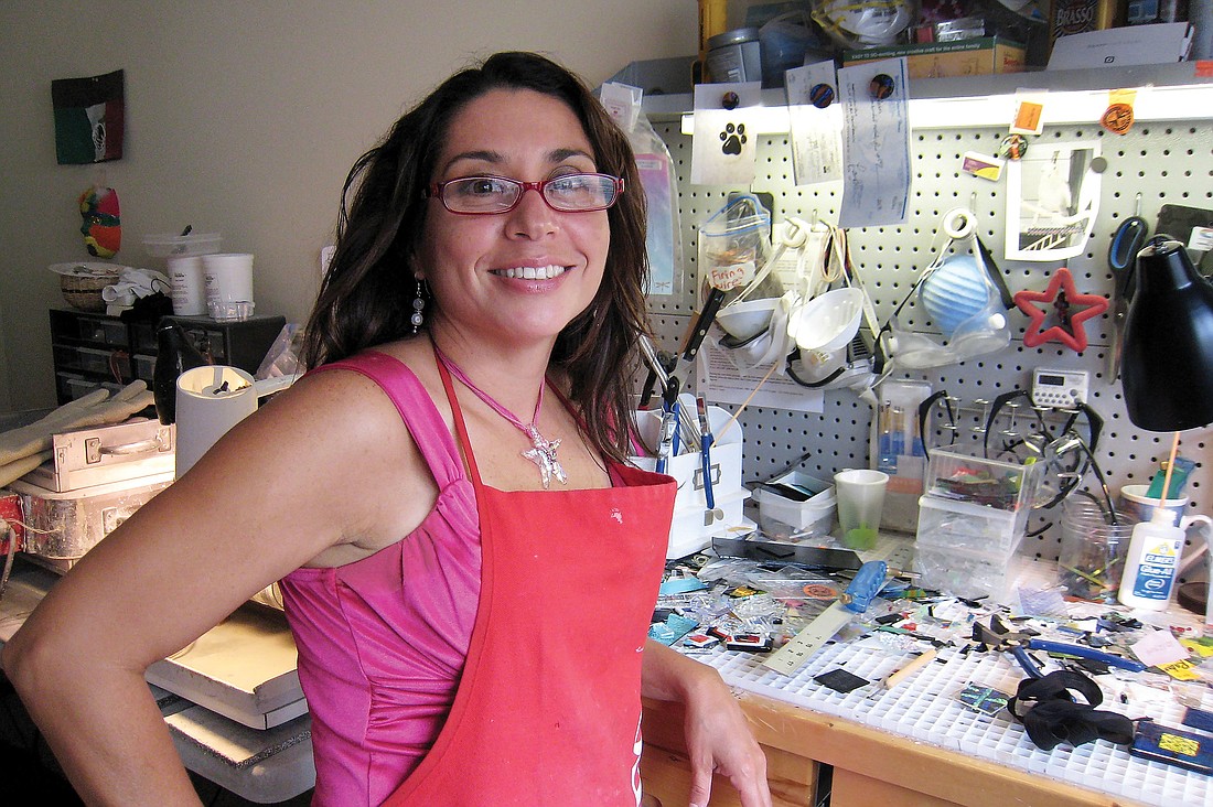 Silvia Engel, wearing one of her customized necklaces, lets light shine through the windows of her home studio and listens to upbeat music when she crafts jewelry made with ashes.