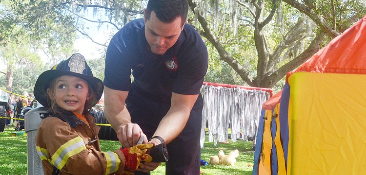 Station 5 firefighter Tommy Lerardi helps Rachel Storino, 3, go through the Junior Fireman Combat Challenge at the Open House.
