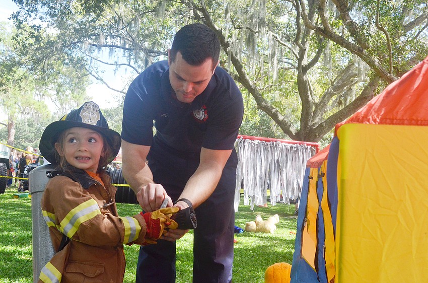 Station 5 firefighter Tommy Lerardi helps Rachel Storino, 3, go through the Junior Fireman Combat Challenge at the Open House.