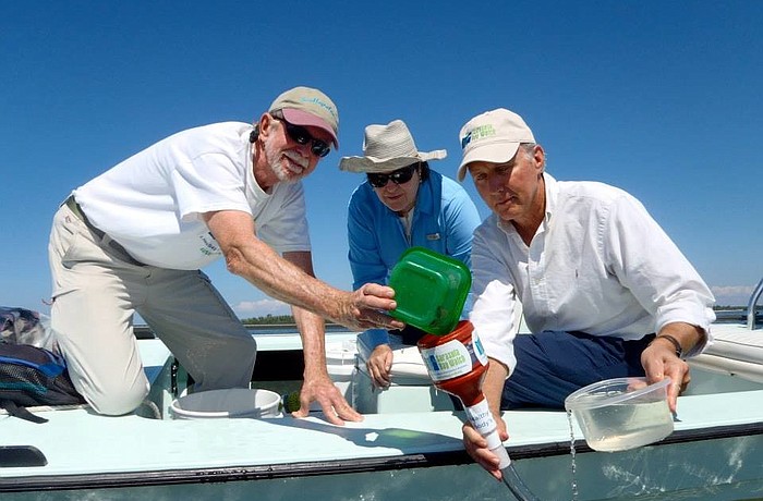 Rusty Chinnis, Caroline McKeon and Manatee County Natural Resources Director Charlie Hunsicker release scallops via a funnel into the bay. (Courtesy Ronda Ryan)