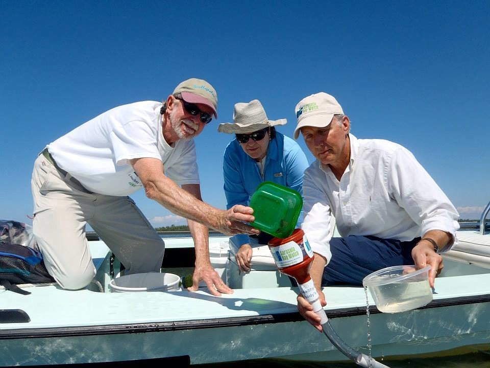 Rusty Chinnis, Caroline McKeon and Manatee County Natural Resources Director Charlie Hunsicker release scallops via a funnel into the bay. (Courtesy Ronda Ryan)