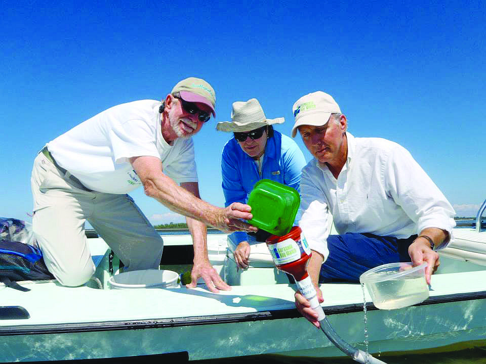 Sarasota Bay Watch founder Rusty Chinnis, board member Caroline McKeon and Manatee County Natural Resources Director Charlie Hunsicker use a funnel to deliver scallops directly into seagrass beds.