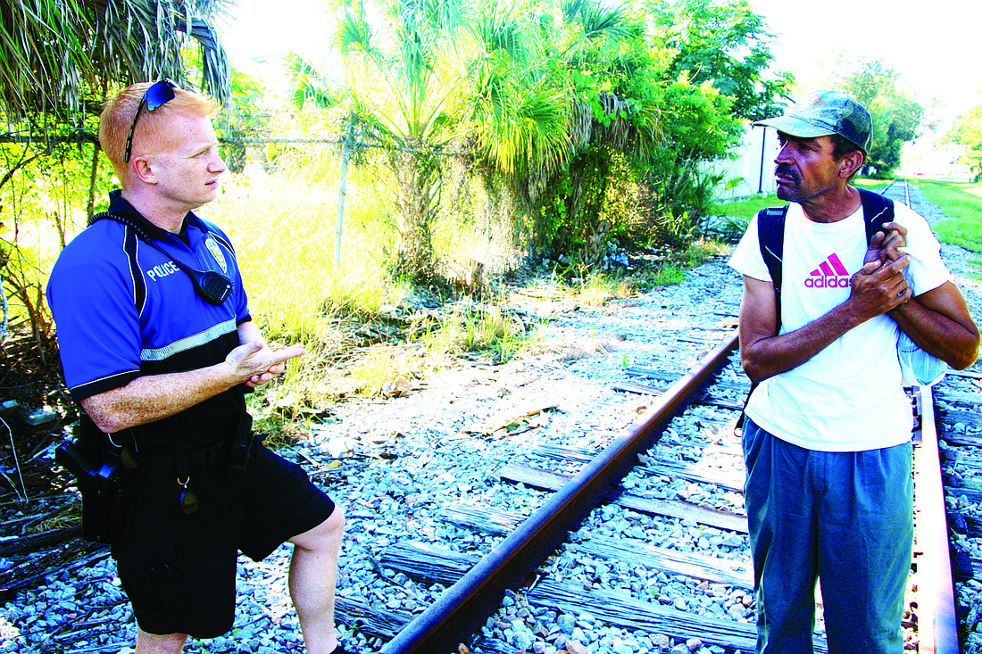 Sarasota police officer David Dubendorf speaks with a homeless man near a series of railway encampments in the city of Sarasota.