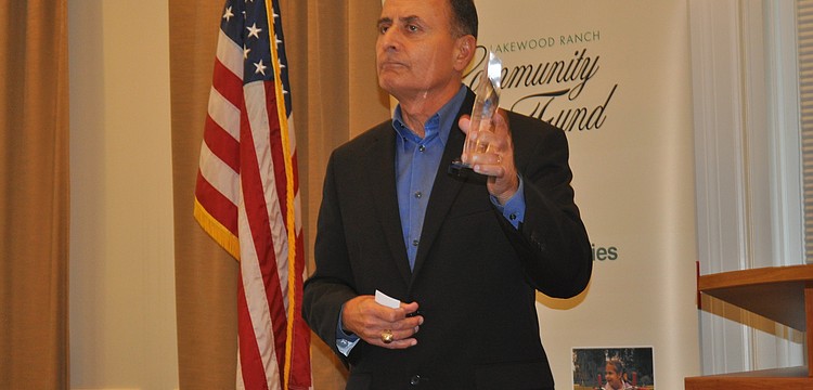 Colonel John W. Saputo, president/owner of Gold Coast Eagle Distributing and former Marine, showed his 2013 C. John A. Clarke Humanitarian Award to the audience.
