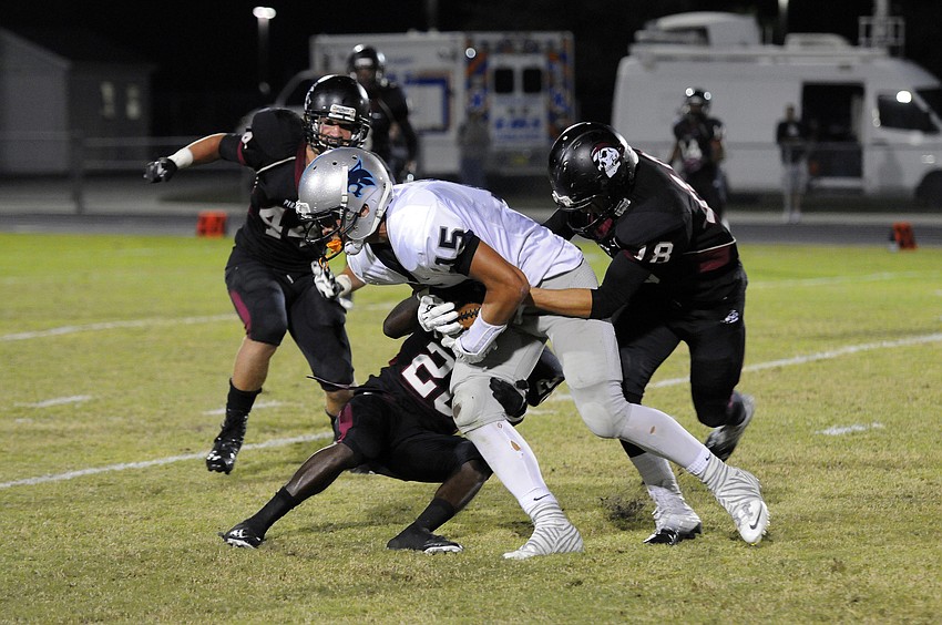 A trio of Braden River defenders bring down North Port wide receiver Sly Augustyn.