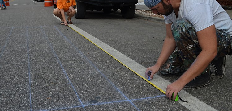 Local chalk artist Truman Adams lays down gridlines for his painting. Adams will be painting a 3-D version of the Statue of Liberty's head.