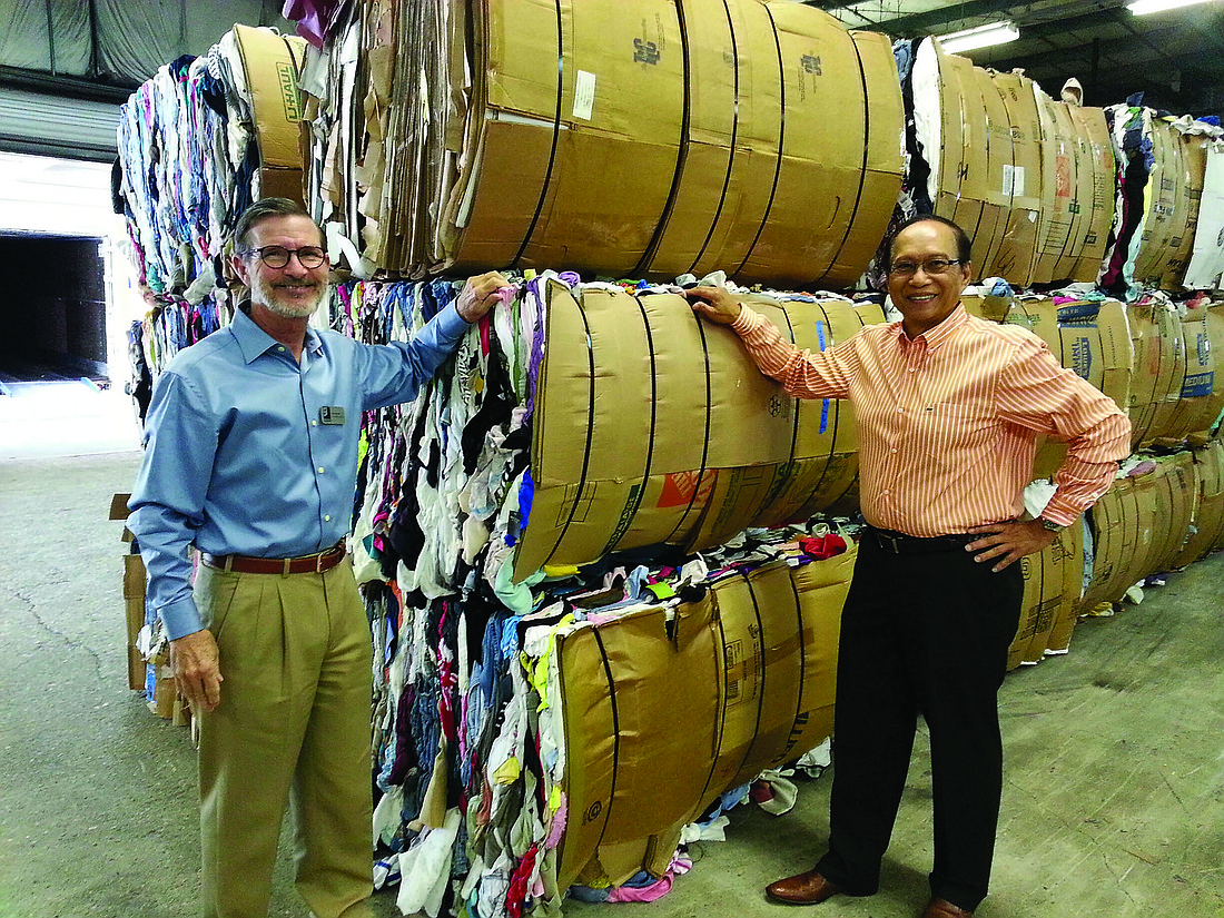 Courtesy photo. Bob Rosinsky, president of Goodwill Manasota, and Fred Lopez gather 43 bales of clothing to be shipped to the Philippines.