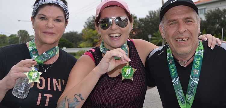 Rene Brent, Kelly Eversole, and David Newell show off their medals after crossing the finish line.