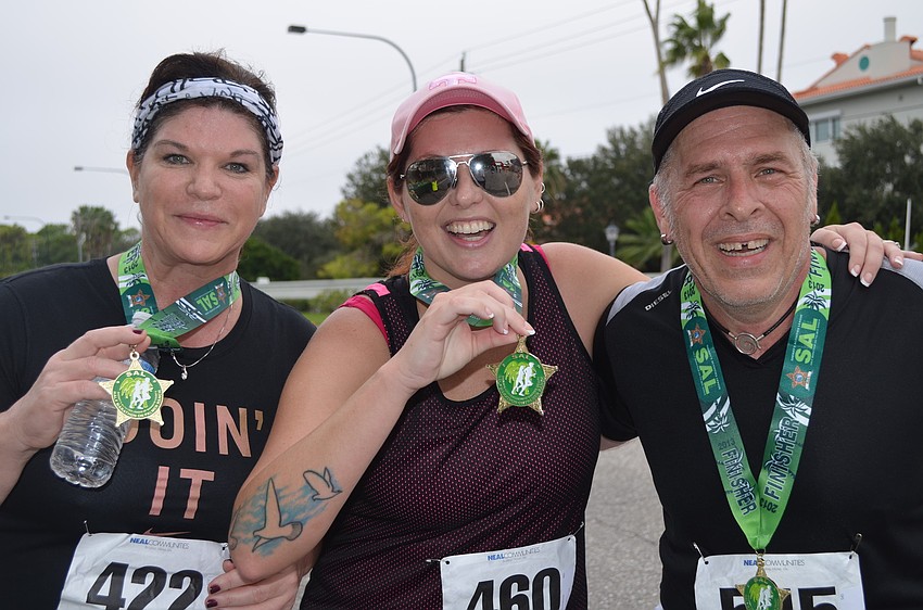 Rene Brent, Kelly Eversole, and David Newell show off their medals after crossing the finish line.