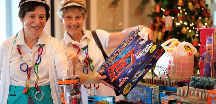 Hannah Weinberg and Anita Cohen add gifts they brought for children in need to a table full of donated toys.