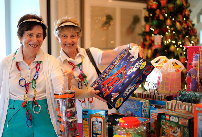 Hannah Weinberg and Anita Cohen add gifts they brought for children in need to a table full of donated toys.