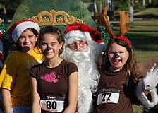 Antonia Forlenza, Jeanni Castro and Kristlyn Ferran sit on Santaâ€™s lap after the run