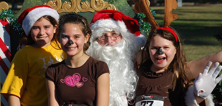 Antonia Forlenza, Jeanni Castro and Kristlyn Ferran sit on Santaâ€™s lap after the run