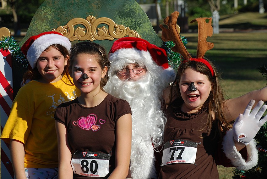 Antonia Forlenza, Jeanni Castro and Kristlyn Ferran sit on Santaâ€™s lap after the run