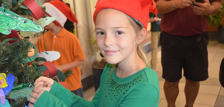 Amelia Miley decorates the tree dressed as an elf.