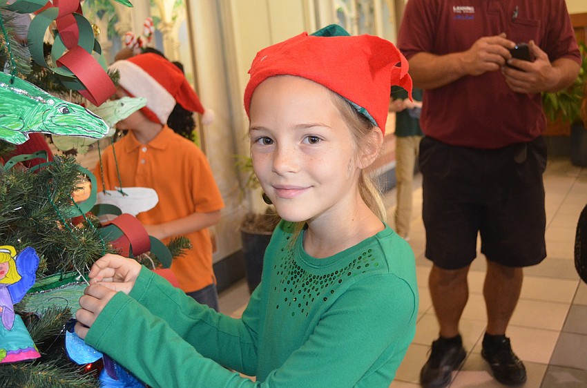 Amelia Miley decorates the tree dressed as an elf.