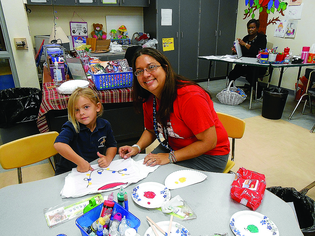 Courtesy photo. Pre-kindergarten student Asylyn Collins and her teacher, Sonya Matson, have a great time creating T-shirts.