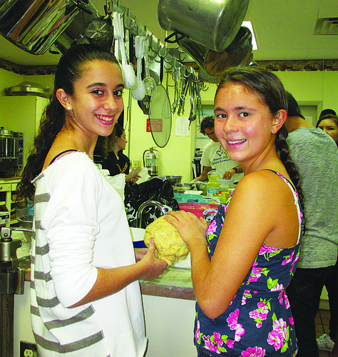 Courtesy from Temple Emanu-El. Allison Kramer and Rachel Towe knead their challah dough.