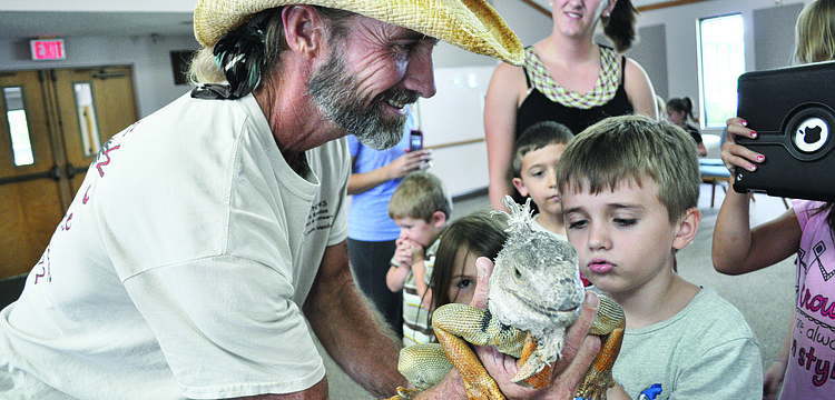 Justin Matthews, of Justin Matthews Wildlife Rescue, shows children Causeway, an iguana, July 26 at All God's Children Preschool, at Living Lord Lutheran Church.