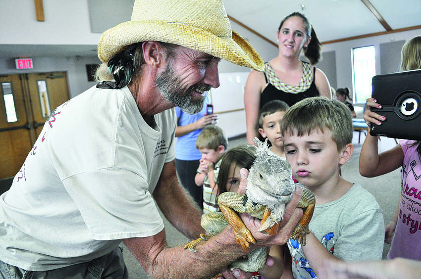 Justin Matthews, of Justin Matthews Wildlife Rescue, shows children Causeway, an iguana, July 26 at All God's Children Preschool, at Living Lord Lutheran Church.