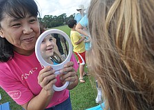 Face painting artist Akiko Campbell shows Abigail Pfeiffer, 6, the rainbow on her face.
