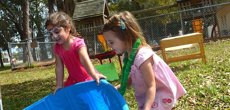 Cousins and 3-year-olds Haven Wood and Madeline Barett try to empty toys out of the pool.