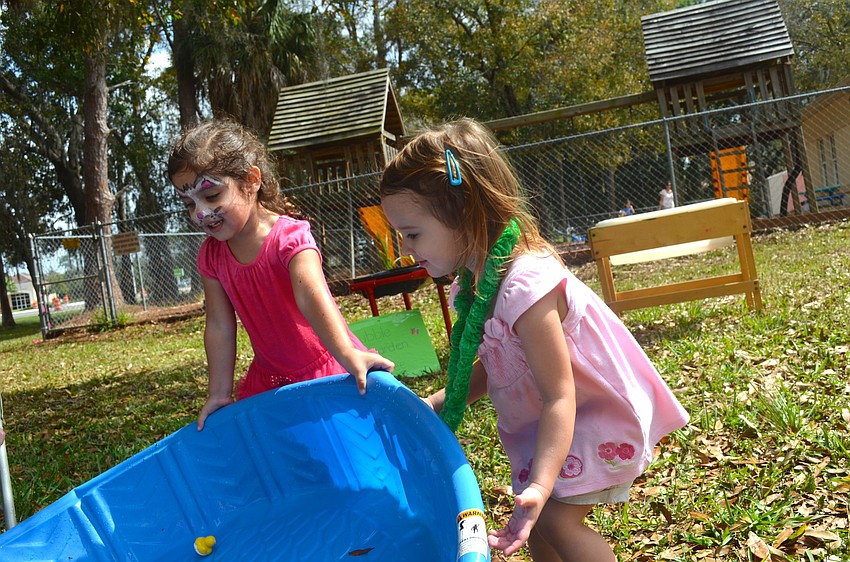 Cousins and 3-year-olds Haven Wood and Madeline Barett try to empty toys out of the pool.