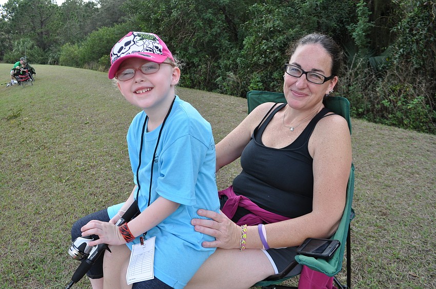 Ashley Hughes fishes from the lap of her mom, Catherine.