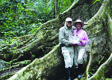 BRANCHING OUT. Longboat residents Ed and Terry Kolodzieski read their Longboat Observer at the roots of a towering tree while at the Pacaya Samiria Reserve in Peru.