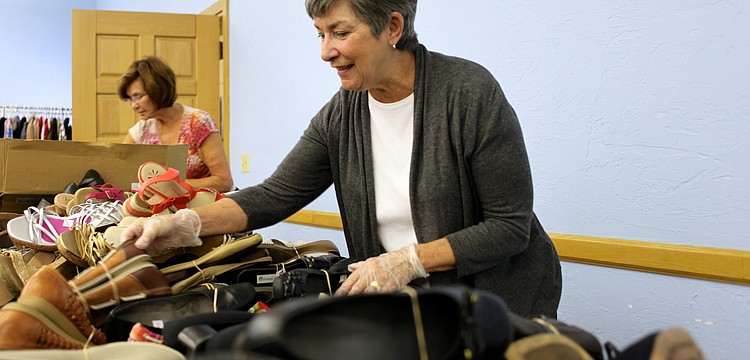 Teri Scaring and Mary DelPup organize shoes into neat piles by size.