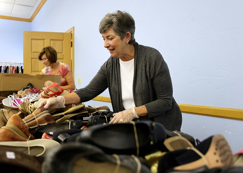 Teri Scaring and Mary DelPup organize shoes into neat piles by size.