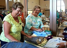 Judy Strauss and Carol Fillmore fold and sort shirts.