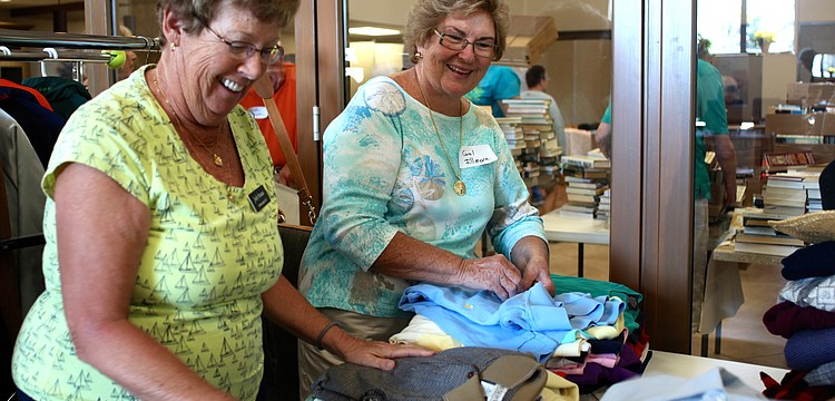 Judy Strauss and Carol Fillmore fold and sort shirts.