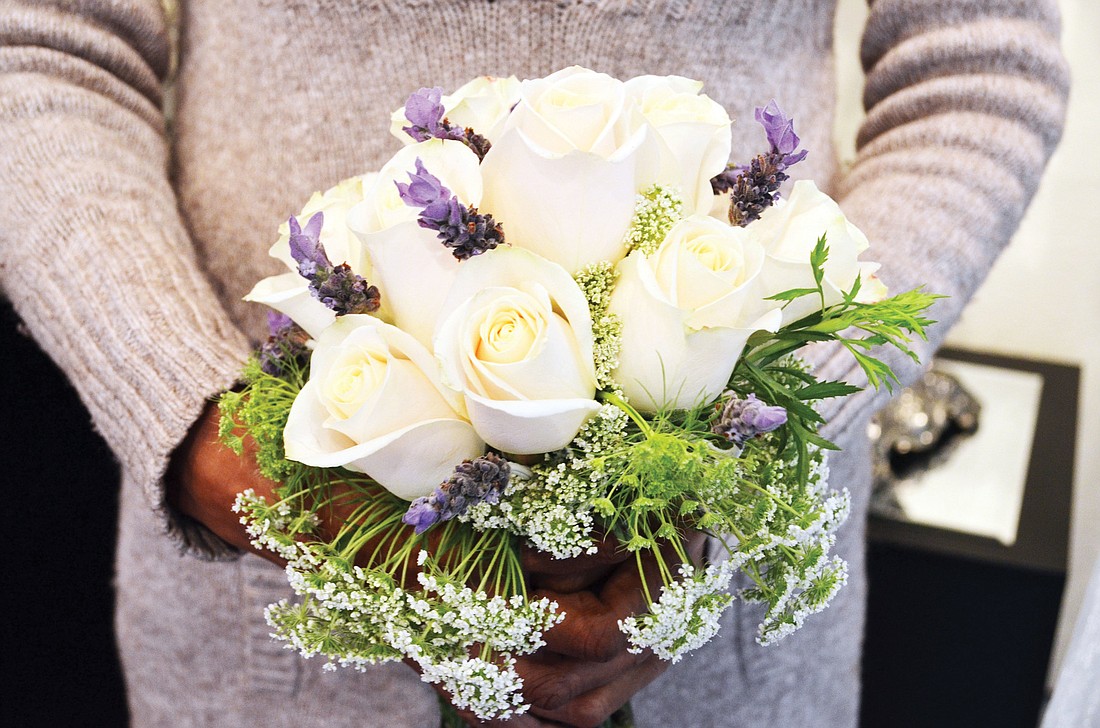 A wedding bouquet at Beneva Flowers made of trendy lilac, Queen Anne's lace, white roses and greenery.