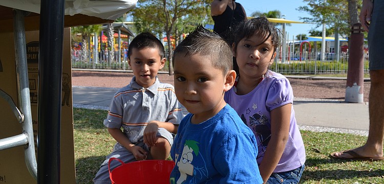 Axel, Brandon and Valeria Espinosa play with rainbow sand.