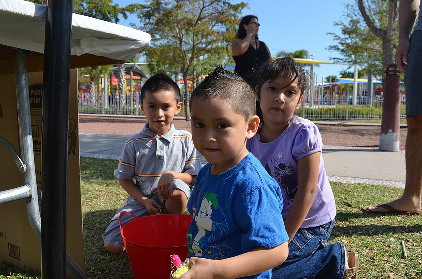 Axel, Brandon and Valeria Espinosa play with rainbow sand.