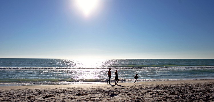 A family visiting from Massachusetts enjoys the sunshine on an afternoon walk along a Longboat Key beach on Tuesday, April 29.