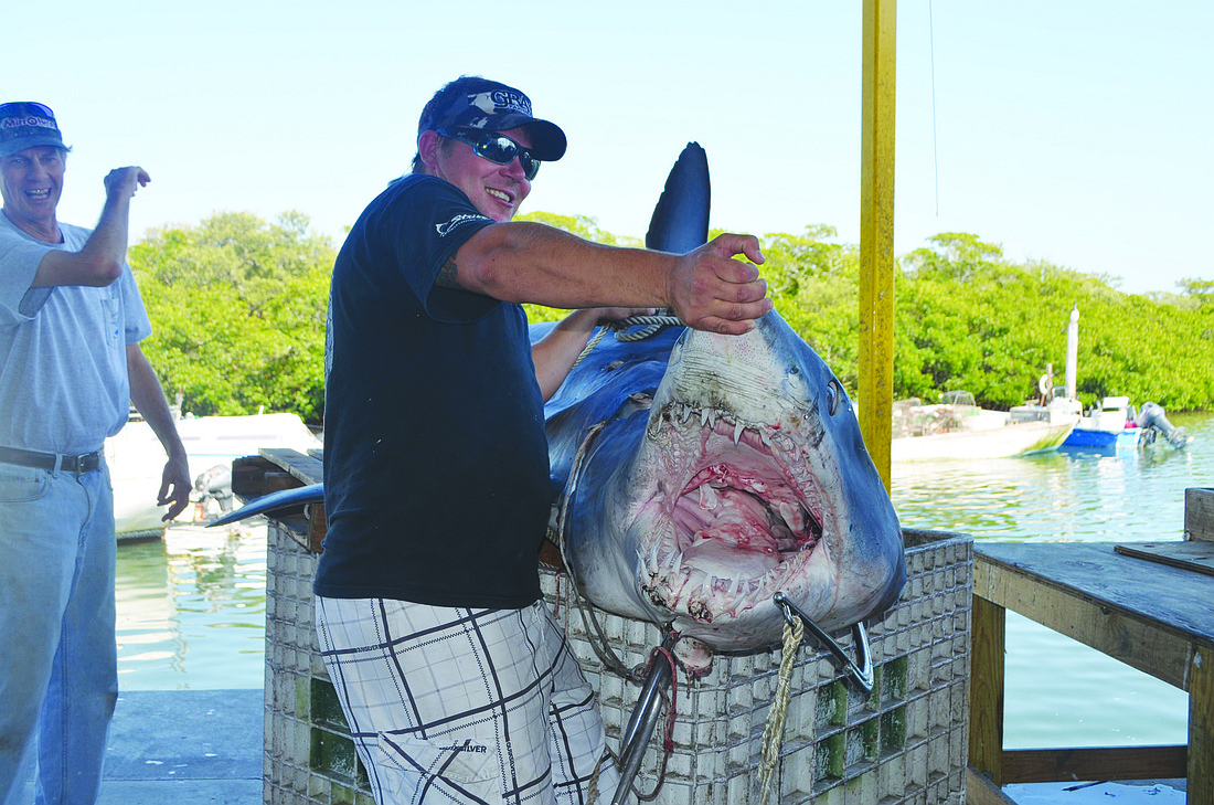 Capt. Nick Froelich shows off the 692-pound shark's giant set of jaws. Photo by Robin Hartill