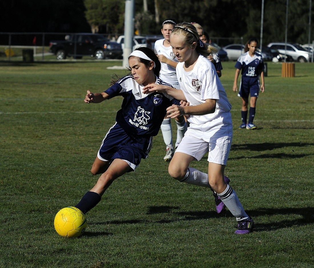 Eleven-year-old Kaylee Cooper battles a Pinecrest Premier midfielder for possession.